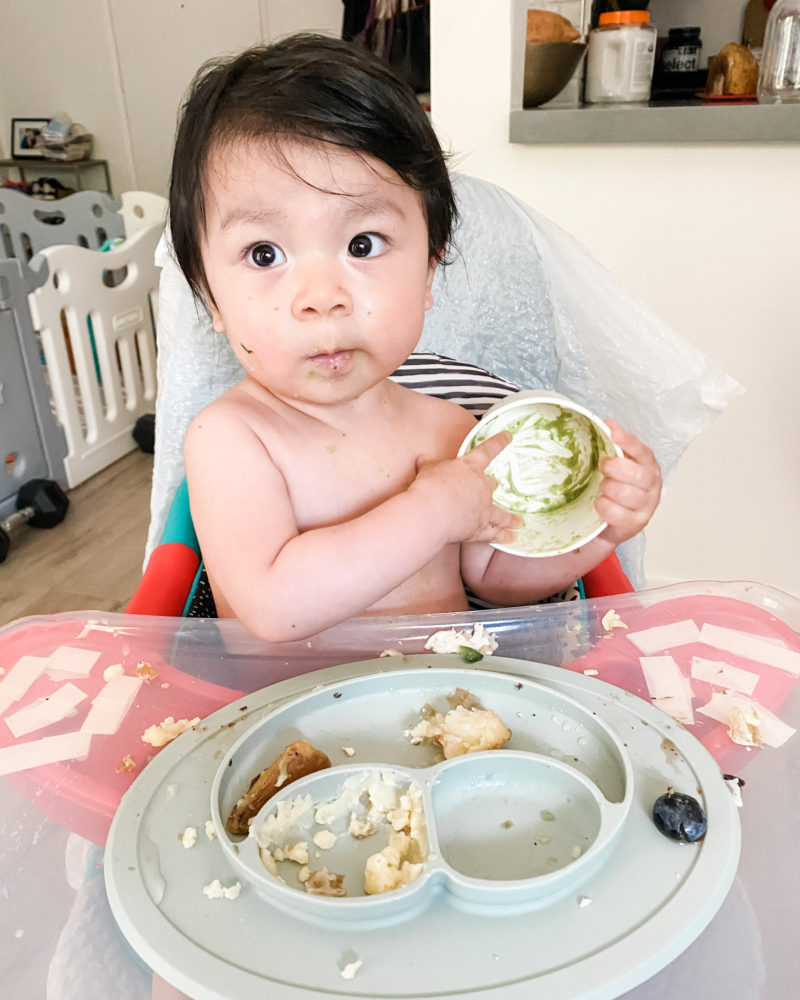 Baby holding container of guacamole